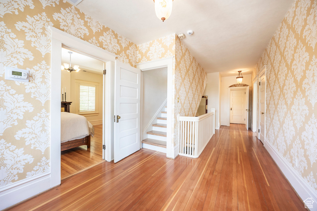 Hallway with an inviting chandelier and hardwood / wood-style flooring