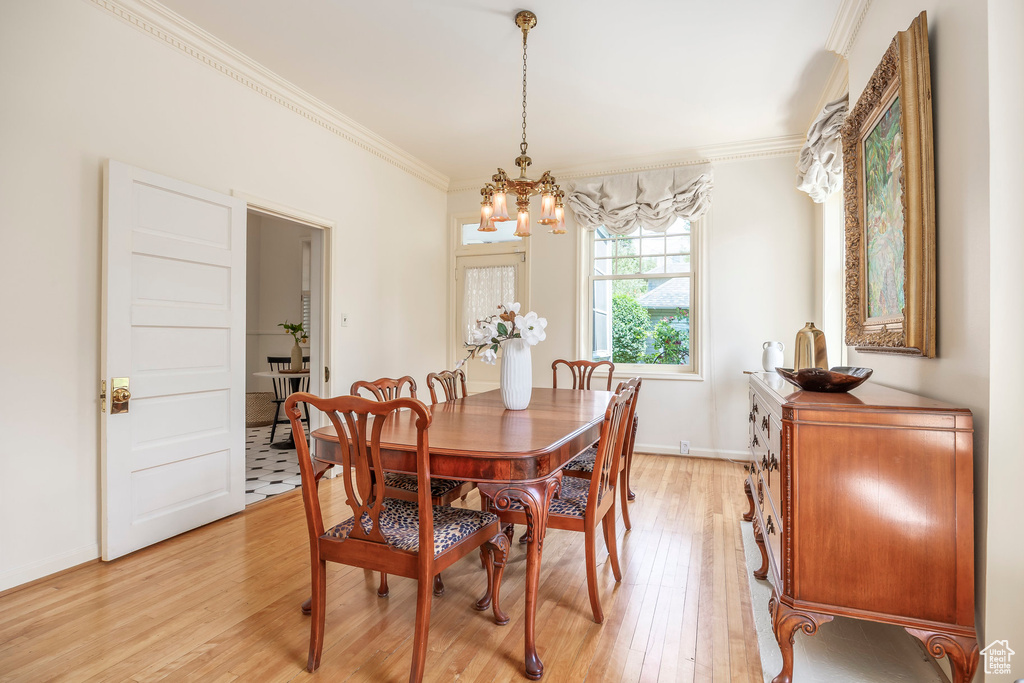 Dining room featuring light hardwood / wood-style floors, ornamental molding, and an inviting chandelier