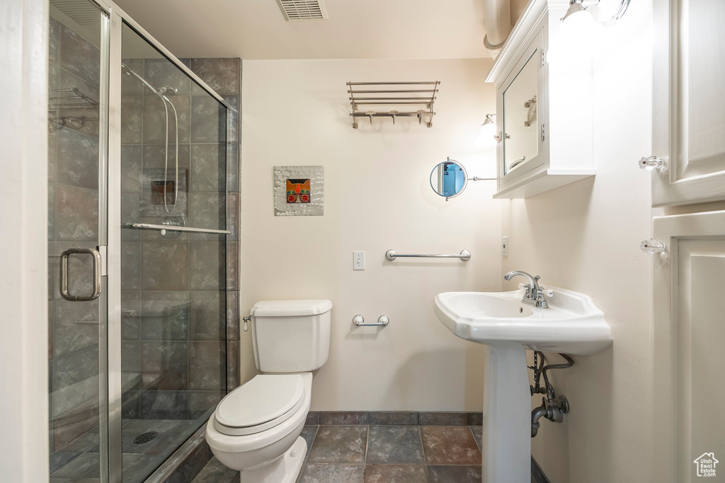 Bathroom featuring walk in shower, tile patterned flooring, and toilet