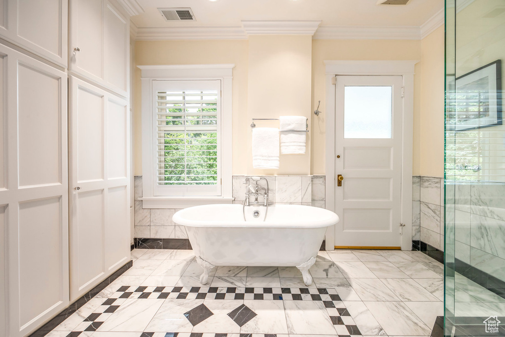 Bathroom featuring ornamental molding, tile walls, a bath, and tile patterned floors