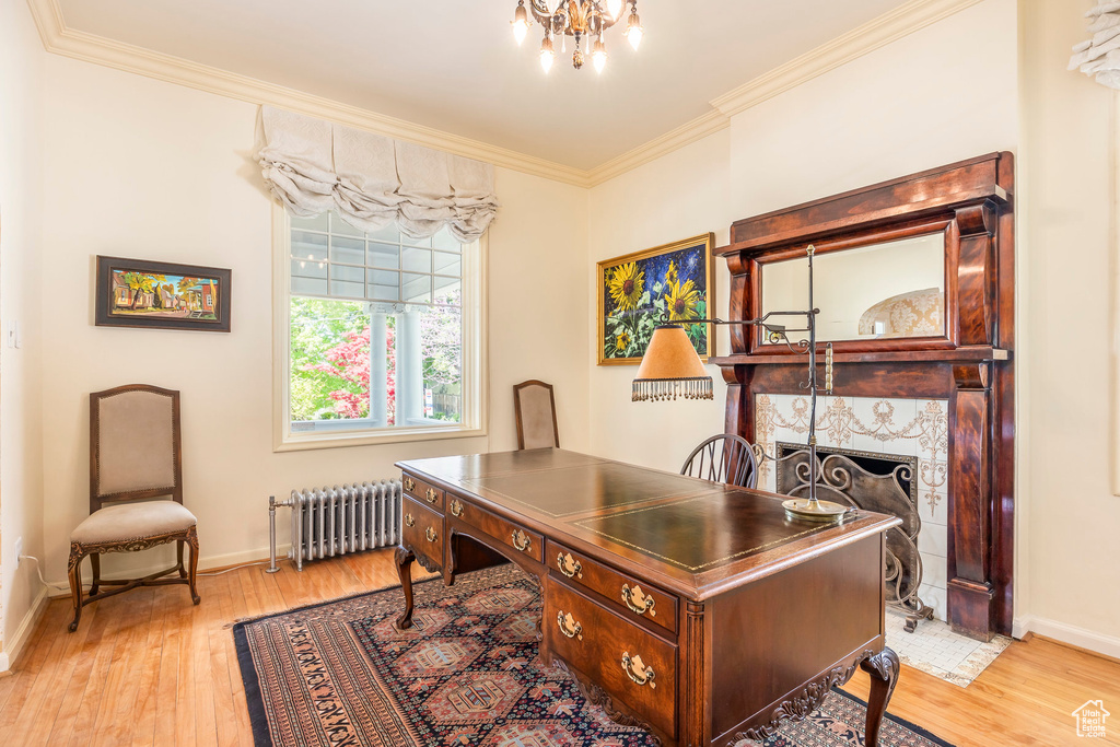 Office area featuring ornamental molding, radiator heating unit, a tiled fireplace, and light wood-type flooring