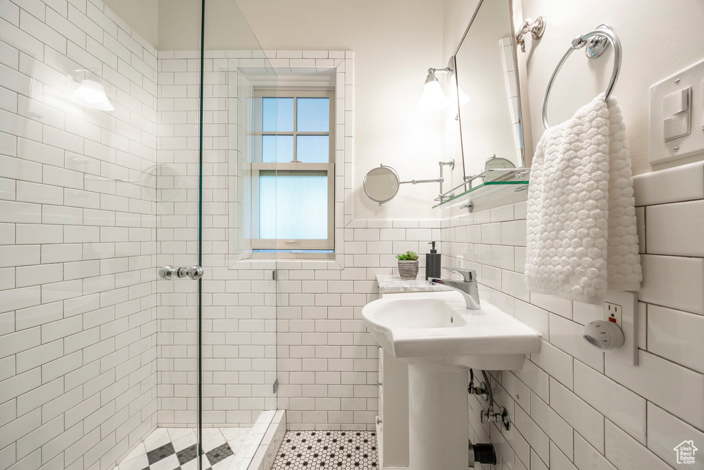 Bathroom featuring decorative backsplash, tile walls, and an enclosed shower