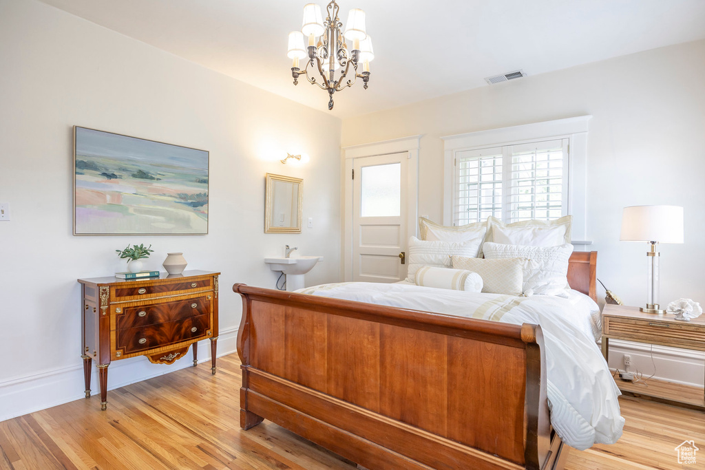 Bedroom with light hardwood / wood-style floors and a chandelier