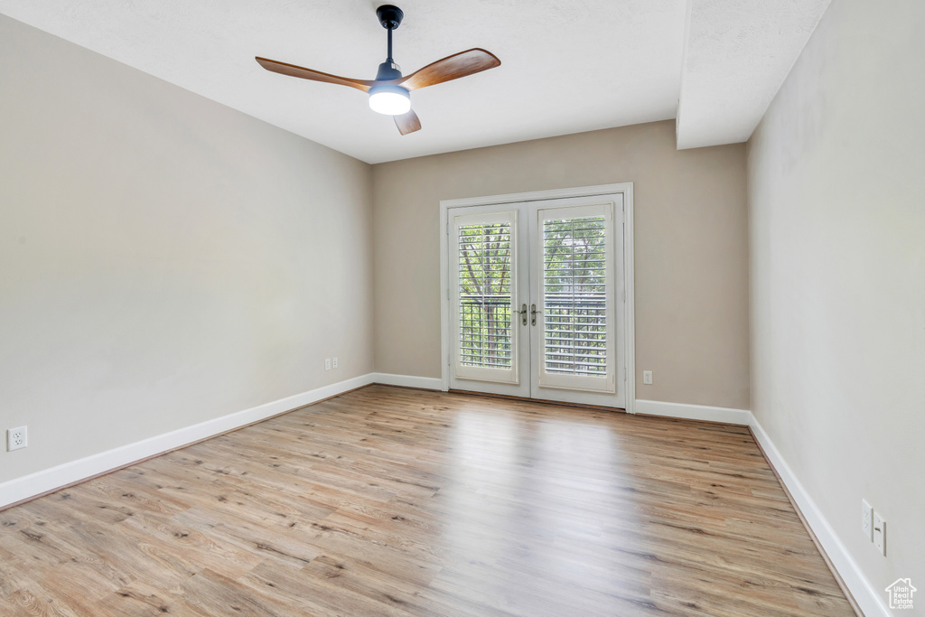 Empty room featuring french doors, ceiling fan, and light wood-type flooring