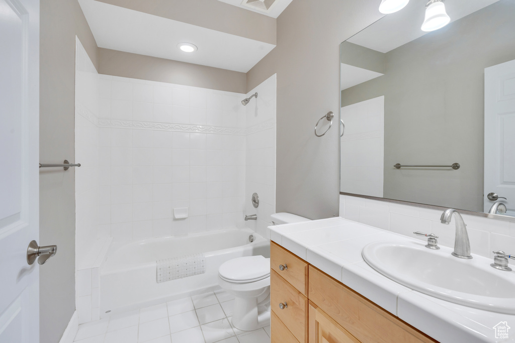 Full bathroom with tile patterned flooring, tiled shower / bath combo, toilet, and vanity