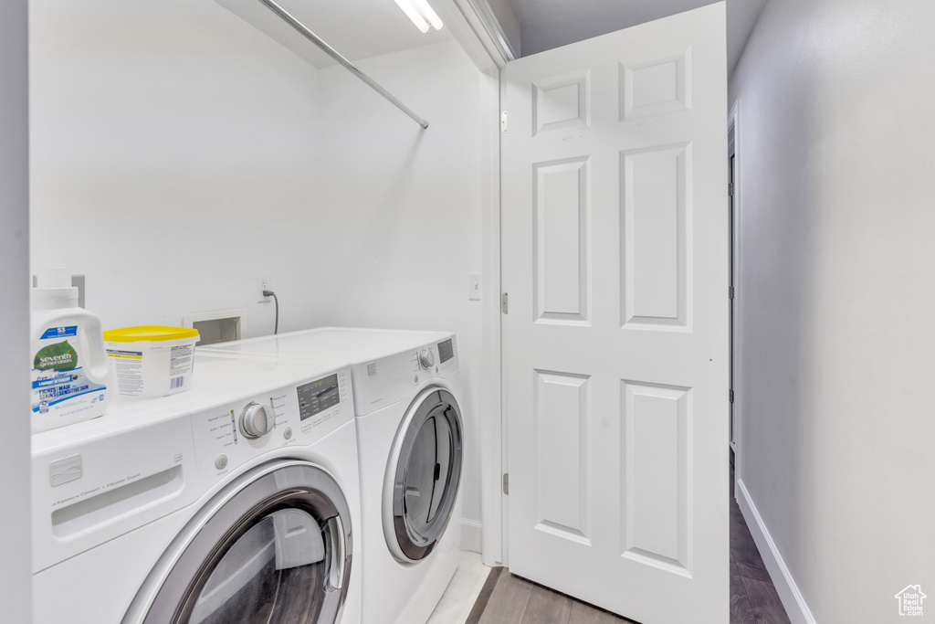 Clothes washing area featuring washer and dryer and hardwood / wood-style floors