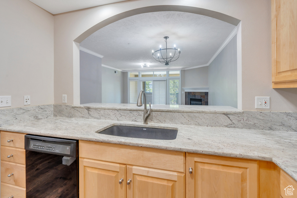 Kitchen with sink, black dishwasher, a tiled fireplace, and crown molding