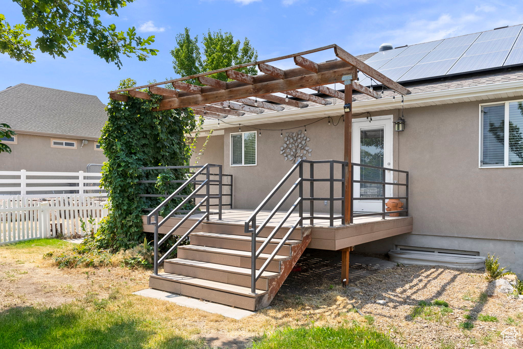 Back of property with a pergola and solar panels