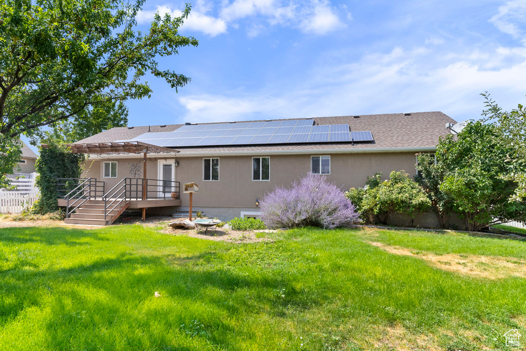 Back of house with solar panels and a yard