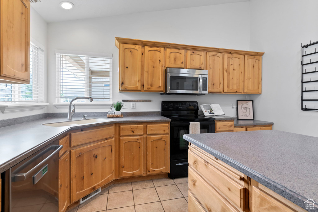 Kitchen with sink, lofted ceiling, light tile patterned floors, and stainless steel appliances