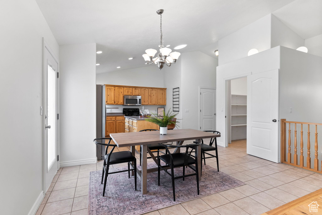 Dining room featuring light tile patterned flooring, high vaulted ceiling, and an inviting chandelier