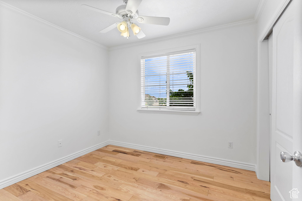 Empty room with ornamental molding, light hardwood / wood-style flooring, and ceiling fan