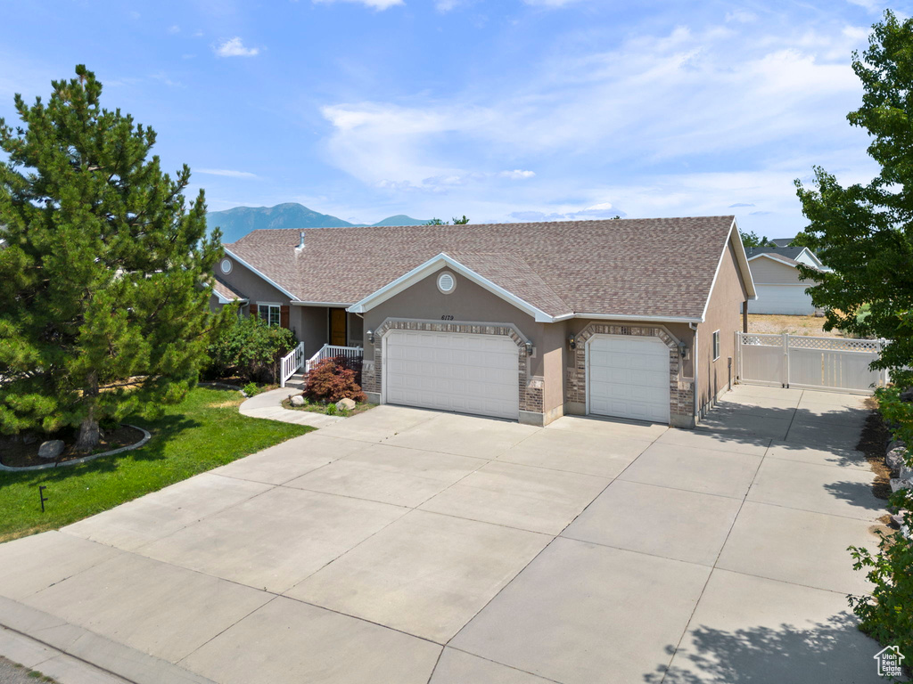 Ranch-style home with a garage, a mountain view, and a front yard