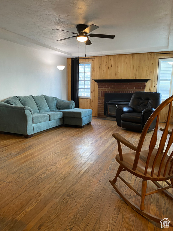 Living room with a fireplace, hardwood / wood-style flooring, and ceiling fan