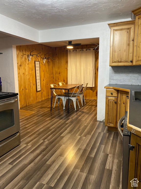 Dining area featuring a textured ceiling, wooden walls, and dark wood-type flooring