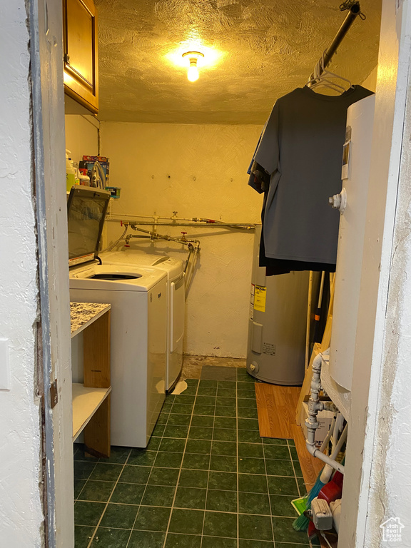 Washroom with dark tile patterned floors, washing machine and clothes dryer, and cabinets