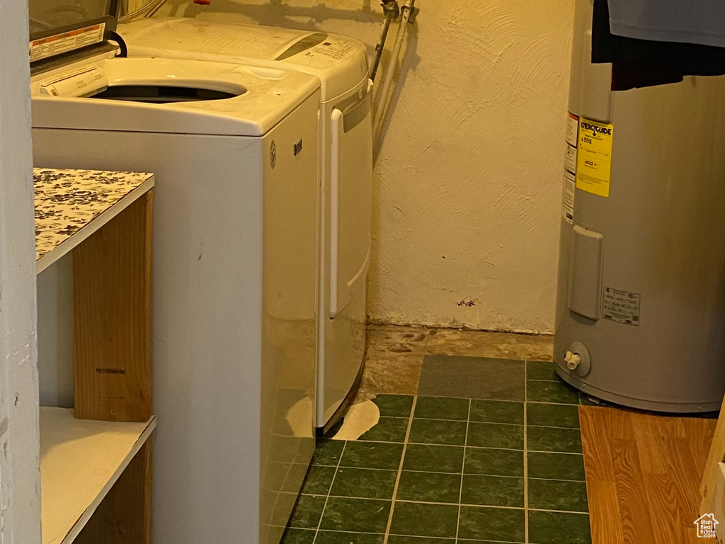 Washroom with dark tile patterned floors, washing machine and clothes dryer, and cabinets