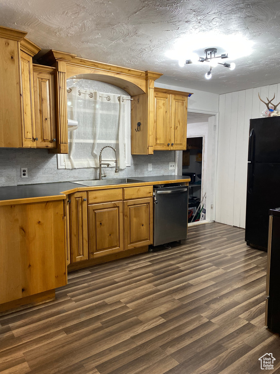 Kitchen featuring dishwasher, backsplash, black refrigerator, dark hardwood / wood-style floors, and sink