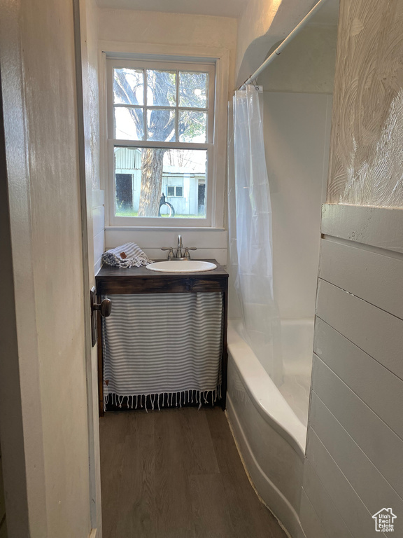 Bathroom featuring hardwood / wood-style flooring, sink, and shower / bath combination with curtain