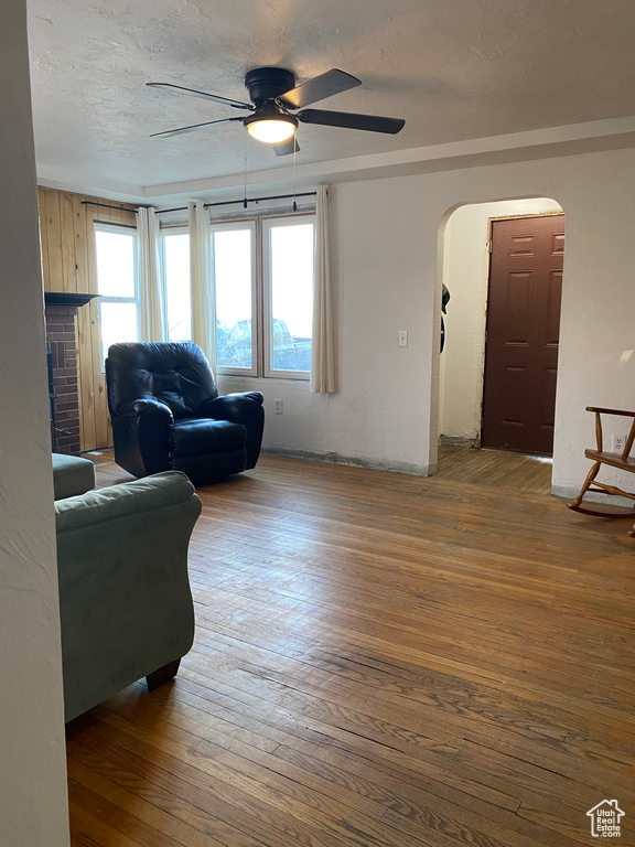Living room with ceiling fan and dark wood-type flooring