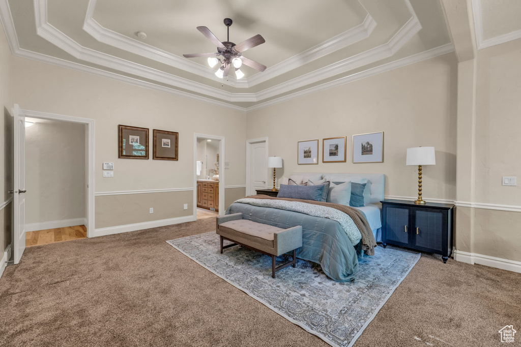 Bedroom with a raised ceiling, carpet, ensuite bath, and ceiling fan