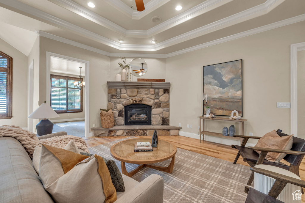 Living room with a fireplace, wood-type flooring, a raised ceiling, and ornamental molding