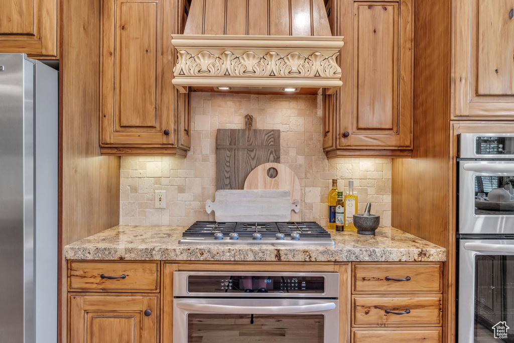 Kitchen featuring custom range hood, backsplash, and stainless steel appliances