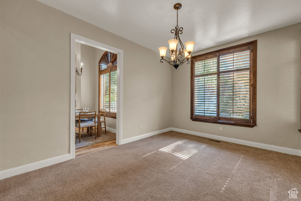 Spare room with carpet flooring and a notable chandelier