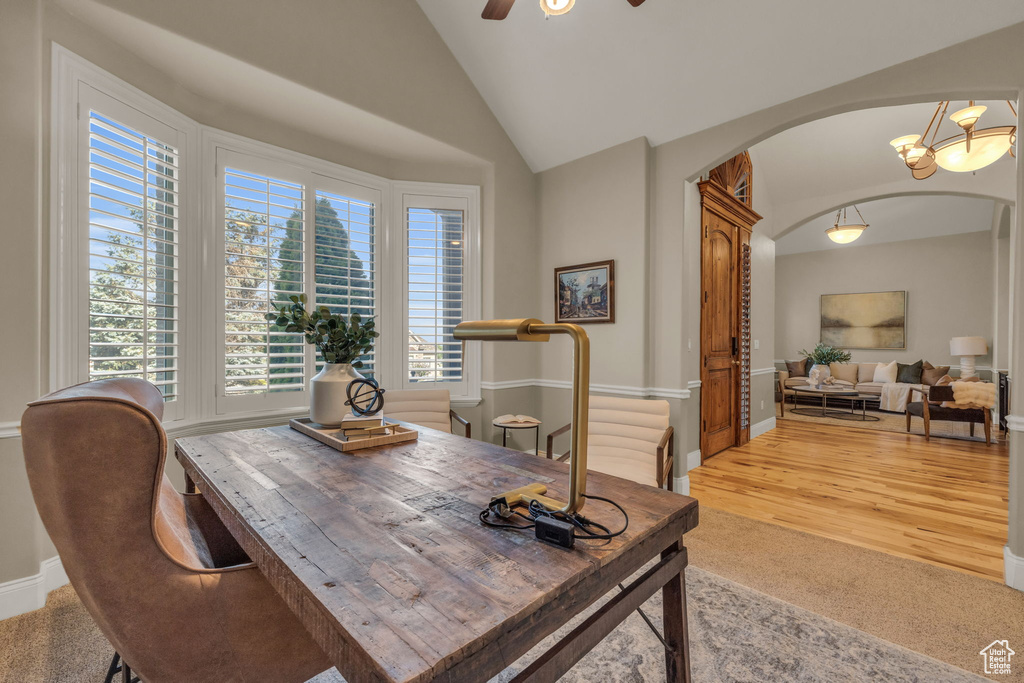 Dining space featuring ceiling fan with notable chandelier, lofted ceiling, and carpet