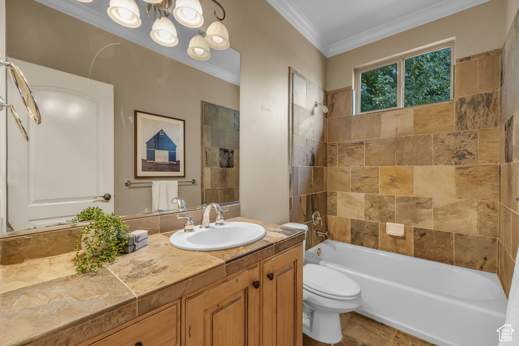 Full bathroom featuring a notable chandelier, vanity, tiled shower / bath, ornamental molding, and toilet