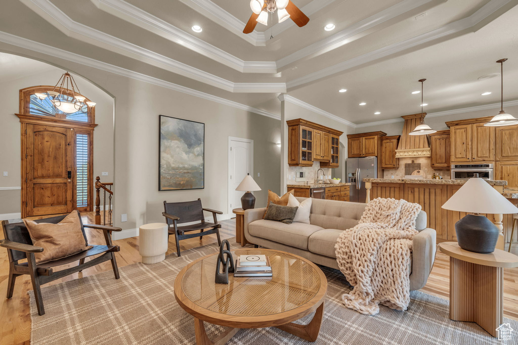 Living room featuring crown molding, a raised ceiling, and ceiling fan