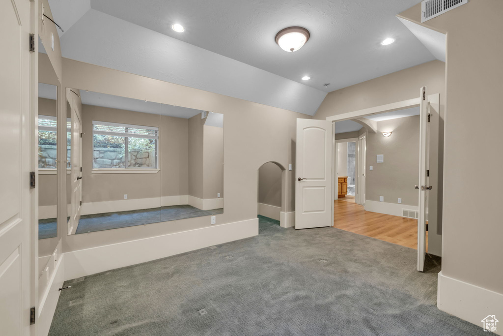 Unfurnished room featuring carpet flooring and vaulted ceiling