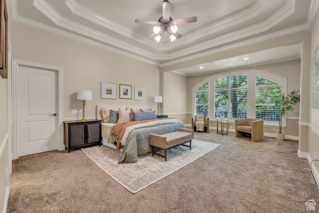 Bedroom with a tray ceiling, ornamental molding, ceiling fan, and carpet flooring