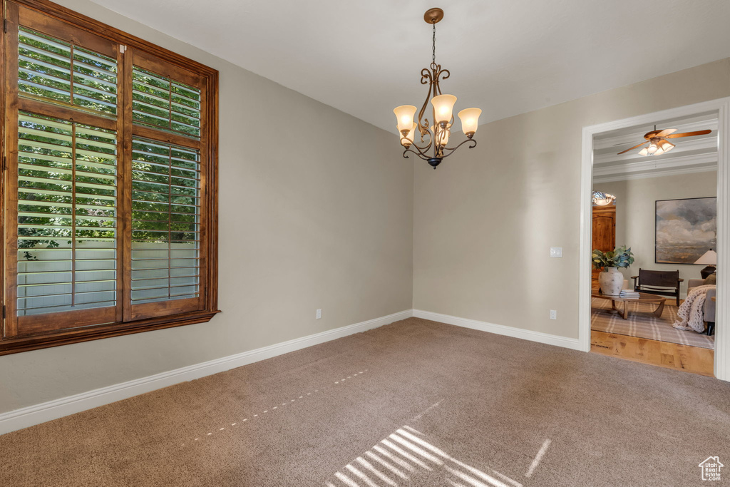 Unfurnished room featuring carpet flooring and ceiling fan with notable chandelier