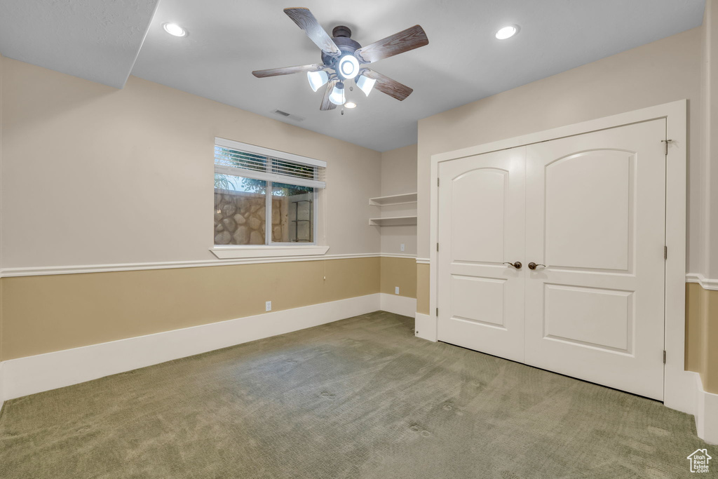 Unfurnished bedroom with dark carpet, a closet, and ceiling fan