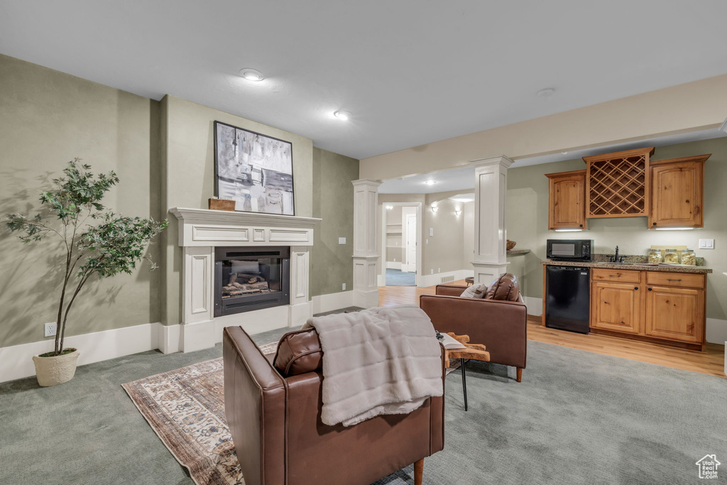 Living room with decorative columns, sink, and light hardwood / wood-style flooring