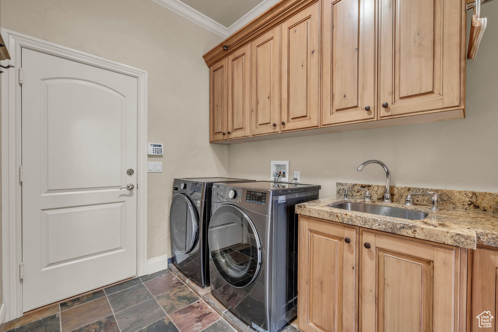 Laundry area with washer and clothes dryer, ornamental molding, sink, cabinets, and dark tile patterned flooring