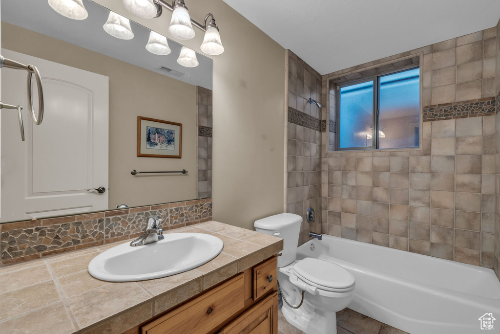 Full bathroom featuring tile patterned floors, vanity, tiled shower / bath combo, and toilet