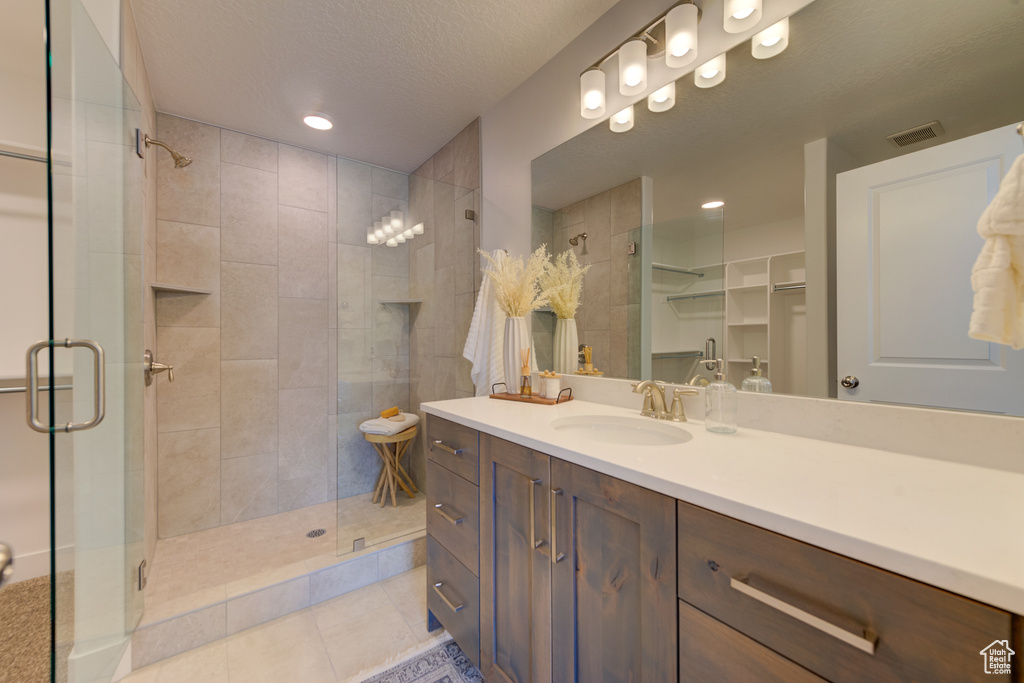 Bathroom featuring vanity, an enclosed shower, tile patterned flooring, and a textured ceiling