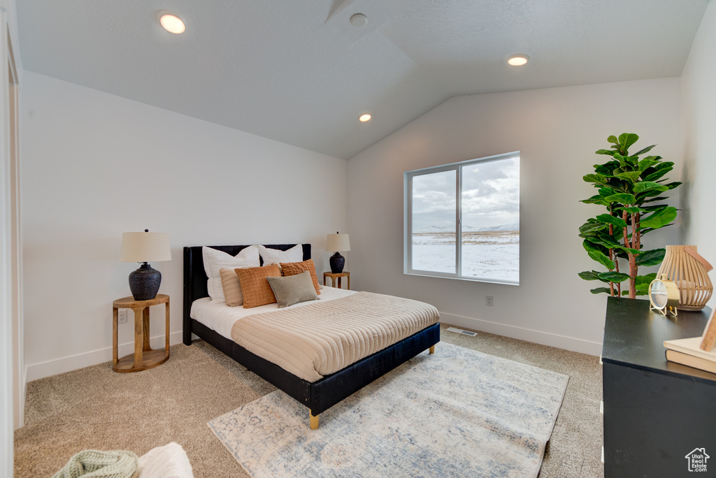 Bedroom featuring light carpet and lofted ceiling