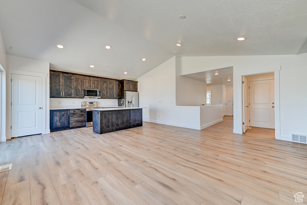 Unfurnished living room with sink, light hardwood / wood-style flooring, and vaulted ceiling