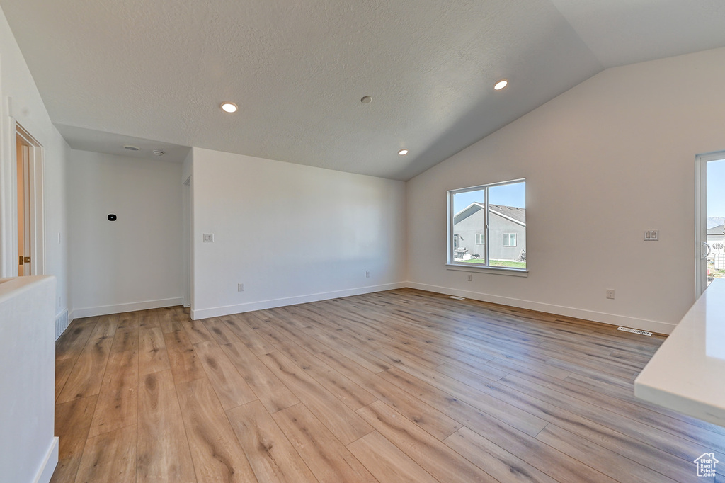 Empty room with lofted ceiling and light hardwood / wood-style flooring