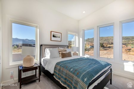 Carpeted bedroom with multiple windows and lofted ceiling