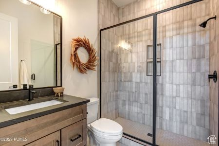 Bathroom with a shower with shower door, vanity, and toilet