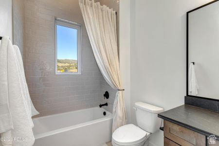 Full bathroom with shower / bath combo with shower curtain, vanity, and toilet