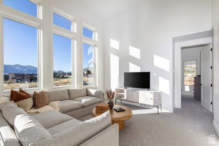 Living room featuring a high ceiling, a mountain view, carpet flooring, and a wealth of natural light