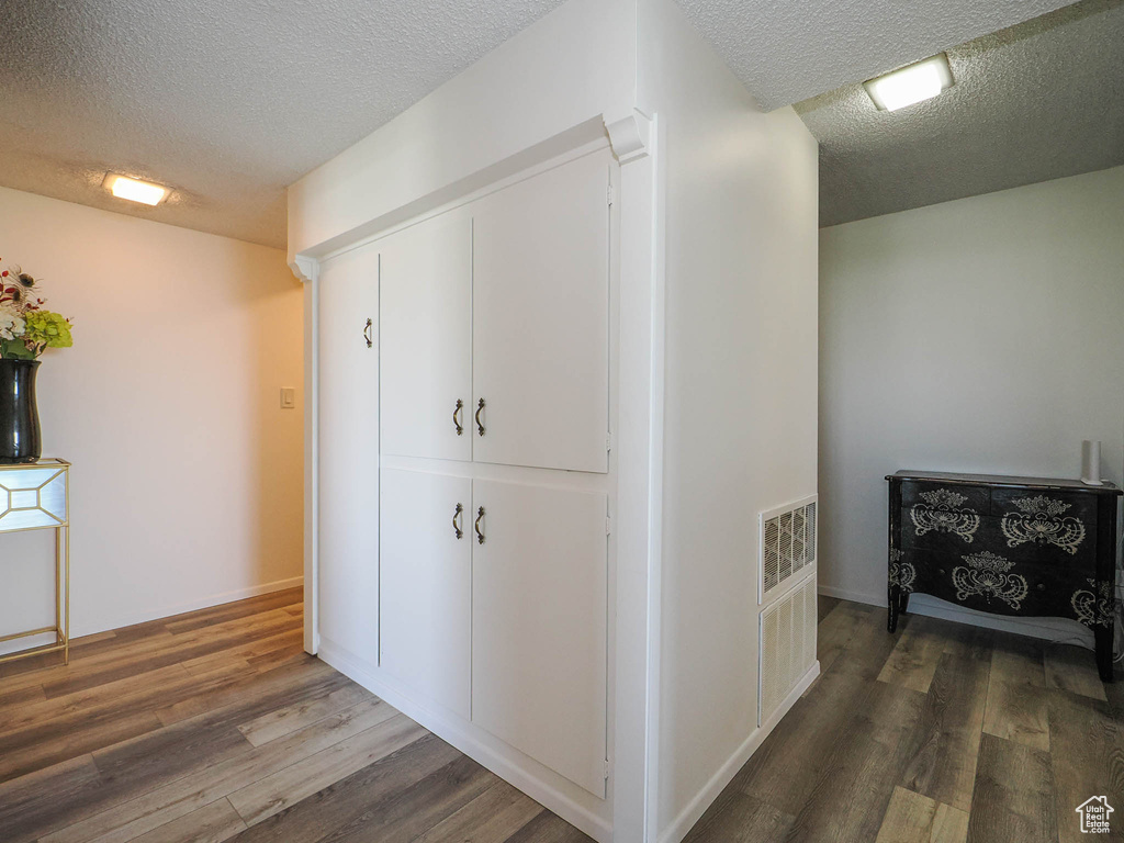 Hallway featuring hardwood / wood-style floors and a textured ceiling