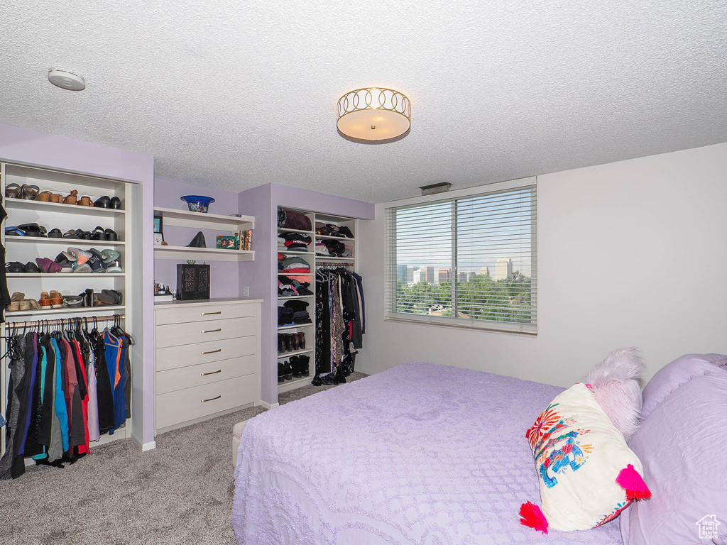 Bedroom with a textured ceiling, a closet, and light colored carpet