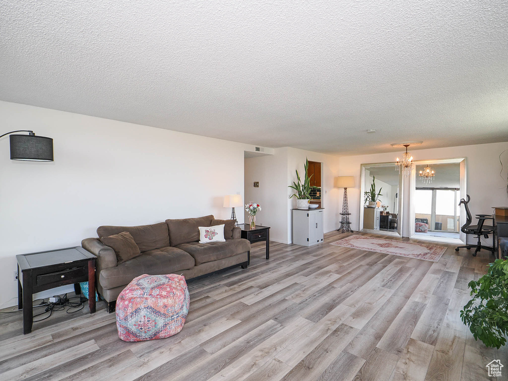 Living room featuring an inviting chandelier, a textured ceiling, and hardwood / wood-style floors