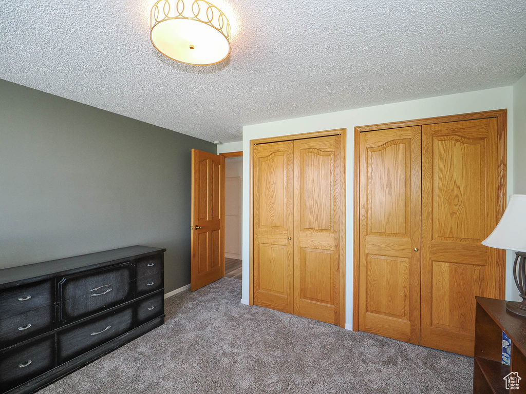 Bedroom with two closets, carpet, and a textured ceiling